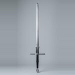 Feder sword with a flat parallel ricasso, a discrete schilt lobe, narrow blade to a broad rolled tip and a black cord wrapped two handed grip shown against a plain studio backdrop