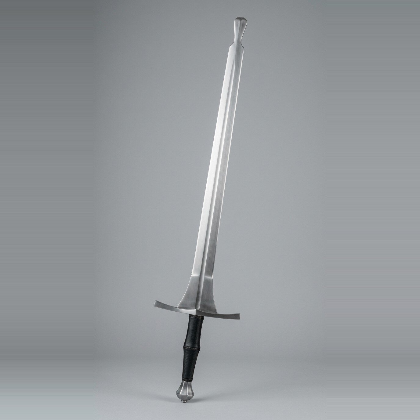 Feder with a flared safety knob tip Feder with a flared safety knob tip, triangular schilt, wide straight cross and a black leather two handed grip shown against a plain studio backdrop