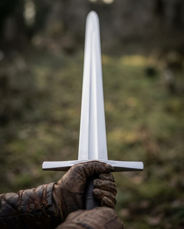 First person view of a high carbon steel arming sword held upright in gloved hands, cross guard and fuller in focus