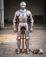 Front view of a polished full plate armour suit on a wooden stand with articulated arms and leather strap fittings