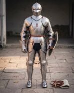 Full suit of polished steel plate armour with visored close helm, gauntlets and sabatons standing in a stone courtyard