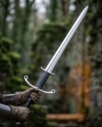 Gloved hands holding a two handed longsword with patterned blade, parry hooks and ring guard against green woodland
