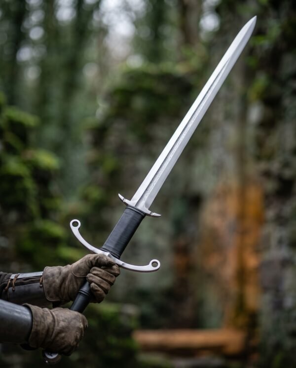 Gloved hands holding a two handed longsword with patterned blade, parry hooks and ring guard against green woodland