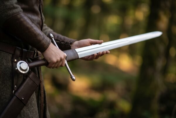 Hand and a half sword with wheel pommel, knobbed cross and leather wrapped ricasso drawn from a belt hung scabbard
