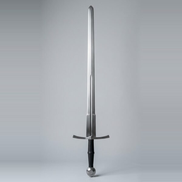 Hand and a half trainer with a narrow fuller, wheel pommel and black waisted leather grip standing point up against a plain grey studio backdrop