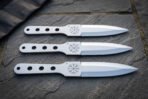 Hand forged 1095 steel throwing knife set of three with Vegvisir etched blades and skeletonised handles laid on dark slate