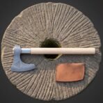 Hand forged Damascus bearded axe with triquetra cheek and ash haft seen from above across a round millstone with its blade cover