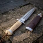 Hand forged Damascus Celtic dagger with carved bone handle, close view of the Elder Futhark etching by the guard and brown sheath