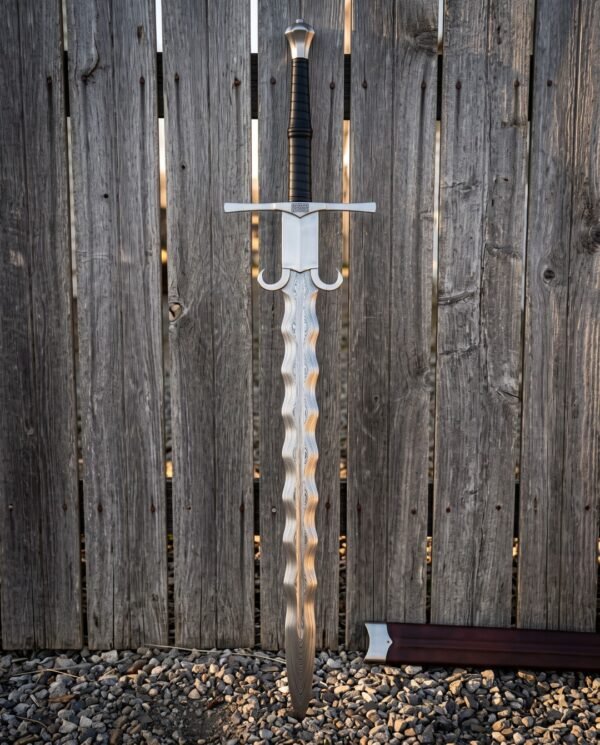 Hand forged damascus flamberge sword standing against a weathered wooden fence, wave cut blade showing layered pattern, parrying lugs and leather wrapped two handed grip