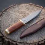 Hand forged Damascus Viking seax with broken back blade, angled view of the rosewood handle and brass bolster on a stump