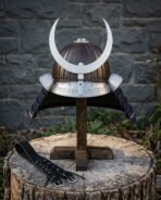 Hand forged kabuto helmet with a ribbed bronze bowl, polished steel crescent crest and rune cut brow band on a wooden stand before a slate wall.