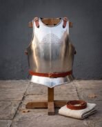 Hand forged steel breastplate in bright 18 gauge mild steel with roped edges, chased Norse knotwork, Elder Futhark runes and russet leather straps on a wooden armour stand