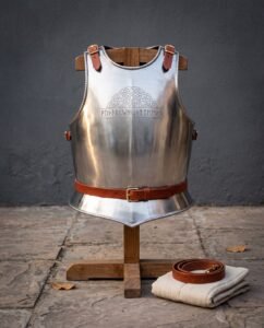 Hand forged steel breastplate in bright 18 gauge mild steel with roped edges, chased Norse knotwork, Elder Futhark runes and russet leather straps on a wooden armour stand