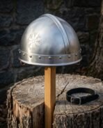 Hand forged steel Viking helmet in the spangenhelm pattern with an engraved Vegvisir and riveted brow band standing on a wooden post before a stone wall