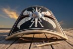 Hand made curved Roman scutum shield with painted wings and steel boss standing on a wooden deck at sunset with fitting kit