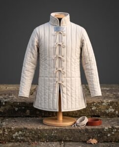 Hand made linen gambeson in natural undyed cloth with vertical channel quilting, tall standing collar and cord loop lacing displayed on a wooden dress stand