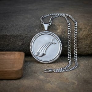 Hand made silver tone bifrost pendant showing the raised rainbow bridge and Asgard gate in a rope twist border, on a heavy curb chain resting against stone