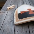 Hand made wooden Templar kite shield with black and white field, red cross pattee and gilt border, low angle on old planks