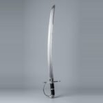 Hanger sabre trainer with a curved single edged blunt blade, D shaped knuckle bow and black leather grip laid against a plain studio backdrop