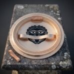Interior of a bronze hoplon shield showing the porpax arm band, leather grip and a painted Gorgon face inside the bowl, resting on a stone plinth