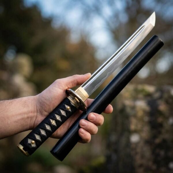 Japanese tanto with polished blade, brass knotwork habaki and black cord over ray skin handle held beside its black scabbard