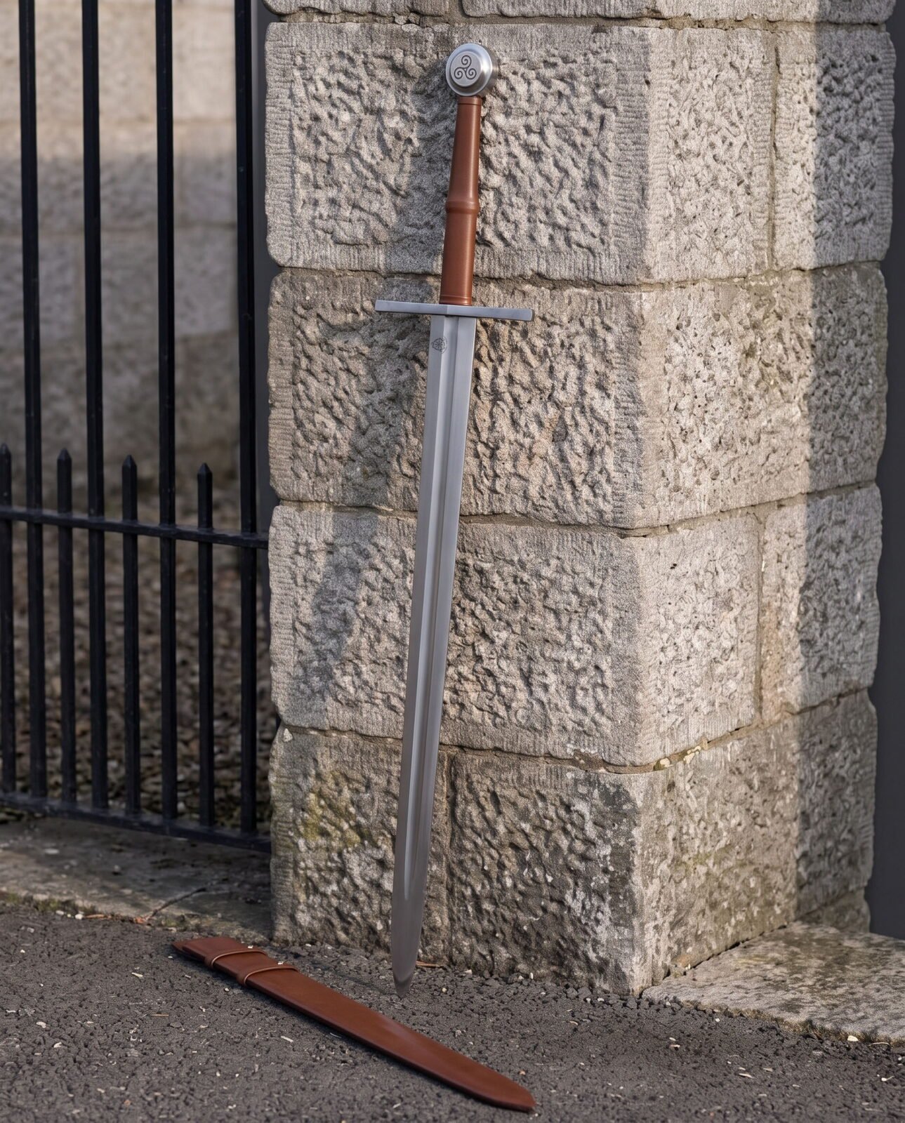 Knightly Norman sword leaning against a granite gate pillar with its russet leather scabbard on the ground, broad fuller Knightly Norman sword leaning against a granite gate pillar with its russet leather scabbard on the ground, broad fullered blade below a triskele engraved disc pommel