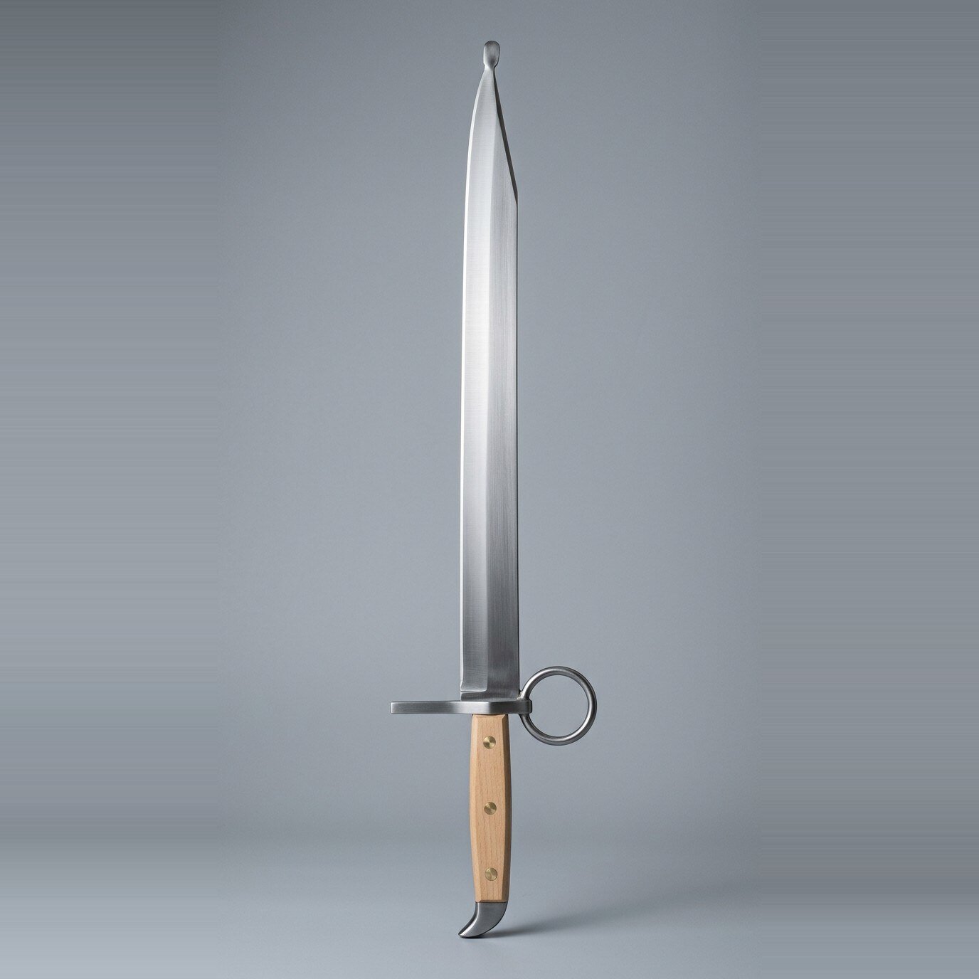 Brunhak Langes Messer Trainer RK-3019 Langes messer trainer with a large ring nagel, three brass rivets through pale wood scales, clipped point and beak shaped butt cap on a plain grey studio backdrop