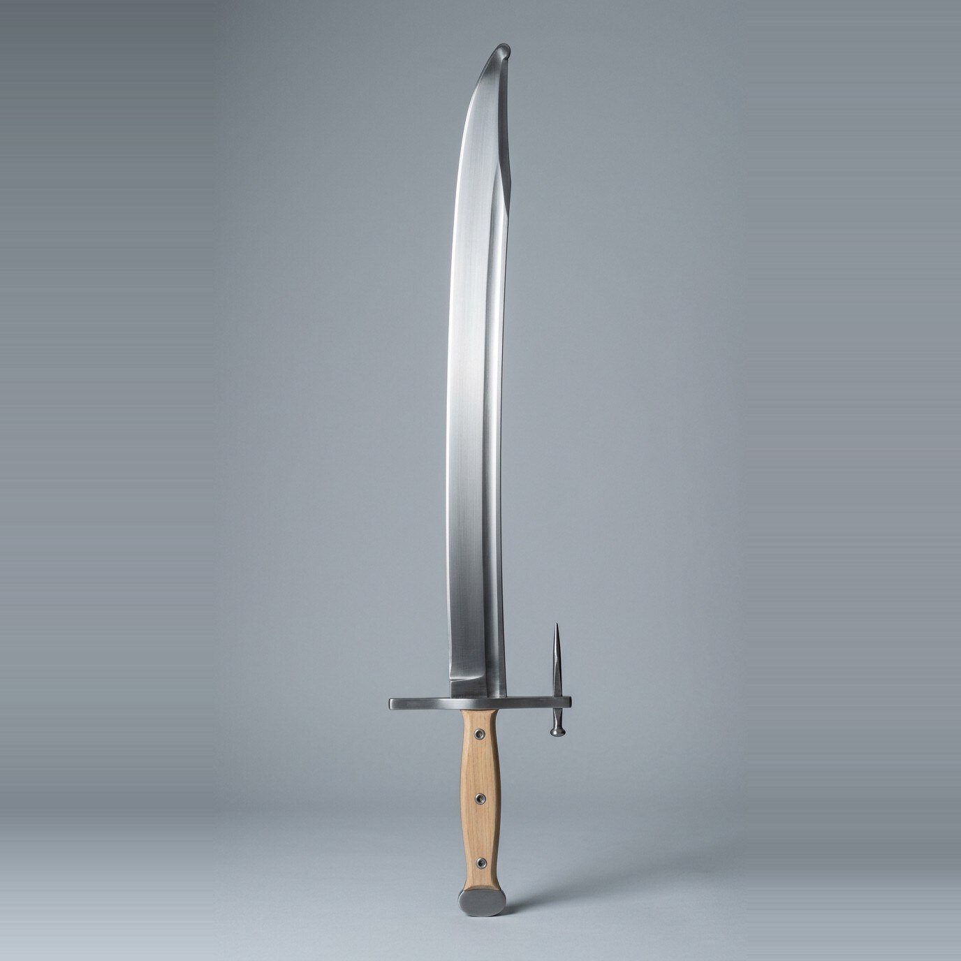 Aurnvik langes messer trainer Langes messer trainer with a long forward angled nagel spike, rounded clipped point and blonde wood scales on three rivets standing point up against a plain grey studio backdrop
