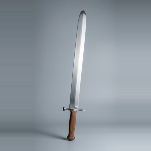 Langes messer trainer with a rounded tip, mushroom head nagel and brown scales on three steel rivets standing point up against a plain grey studio backdrop