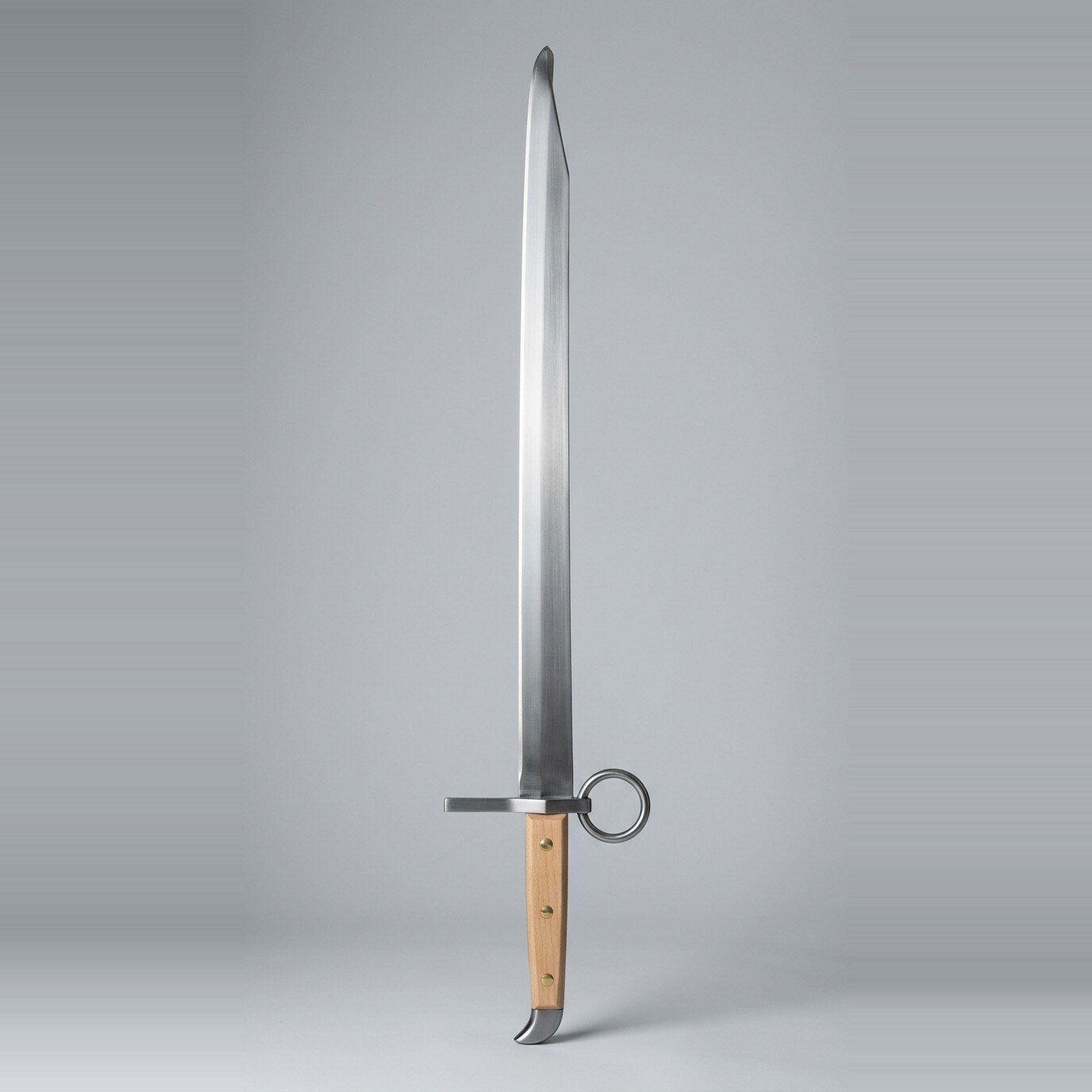 Brenvald langes messer trainer RK-3006 Langes messer trainer with a single edged blunt blade, ring nagel on the flat, three brass rivets through pale wood scales and a beak shaped butt cap on a plain studio backdrop