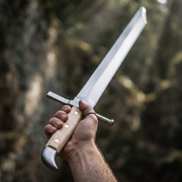 Messer with clipped point, polished beak cap and riveted wood grip held up against a dark forest backdrop