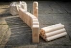 Natural maple kubb lawn game set with Valknut engraved king, row of kubbs, throwing batons and canvas bag on stone paving
