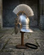 Polished steel Roman imperial helmet with cream horsehair crest and brass brow band on a wooden stand, side view with cheek guards open