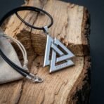 Polished steel valknut pendant with three interlocked triangles and a rune stamped base, black cord with a lobster clasp on split oak