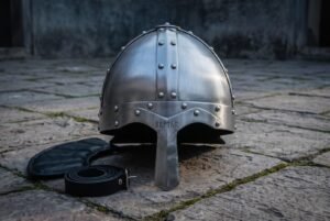 Riveted viking nasal helmet in brushed steel with Elder Futhark runes on the brow band, sitting on mossy flagstones beside its padded liner and chin strap