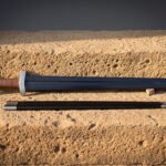 Roman gladius laid on a warm sandstone block beside its dark leather scabbard, blackened ridged blade tapering from a knotwork engraved guard and pale disc pommel
