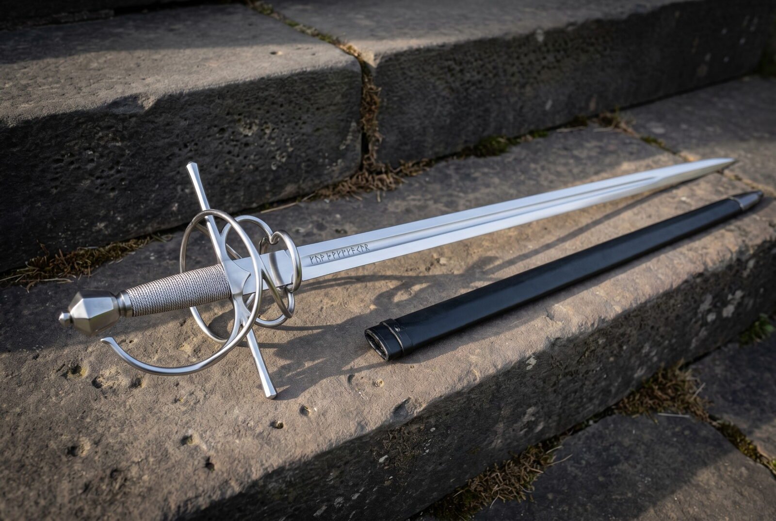 Rune etched rapier with a swept steel hilt and wire wrapped grip lying across weathered stone steps beside its black sca Rune etched rapier with a swept steel hilt and wire wrapped grip lying across weathered stone steps beside its black scabbard in low evening sunlight