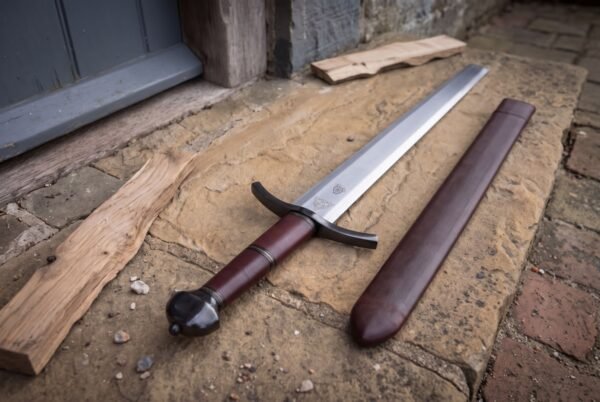 Satin finished arming sword blade under a blackened guard curved toward the edge at both ends