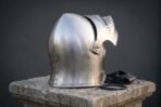 Satin steel sallet helmet with raised visor, hinged temple pivot and chased vegvisir on the skull, side view on a stone plinth