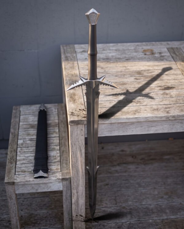 Serrated fantasy sword in low sunlight beside a bench, showing the saw toothed guard wings, cord wrapped grip and faceted knotwork pommel above a satin grey blade