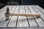 Side view of a polished cross pein hammer showing the wedge pein and knotwork band on a light wood handle