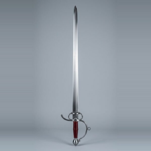 Sidesword trainer with two finger rings, a knuckle bow ending in a free scroll, side ring and oxblood leather grip standing point up against a plain grey studio backdrop