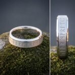 Silver tone rune ring with engraved elder futhark band and bevelled polished edges on moss, with a side view of the runes