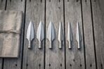 Six polished socketed spearheads, three broad leaf heads and three narrow points, laid in a row beside a rolled canvas wrap