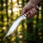 Steel kukri knife with rosewood scales and brass bolster held in hand in sunlit woods, small wolf head etched on the polished blade near the bolster
