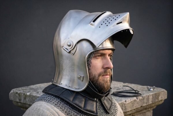 Steel sallet helmet with the visor raised worn by a bearded man in a chainmail coif and quilted collar, shown in profile