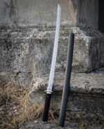Straight Damascus ninjato with angled tip and cord wrapped grip leaning against stone steps next to its lacquered scabbard