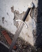 Thirty inch Damascus blade below a swept steel crossguard, black leather grip banded with brass wire