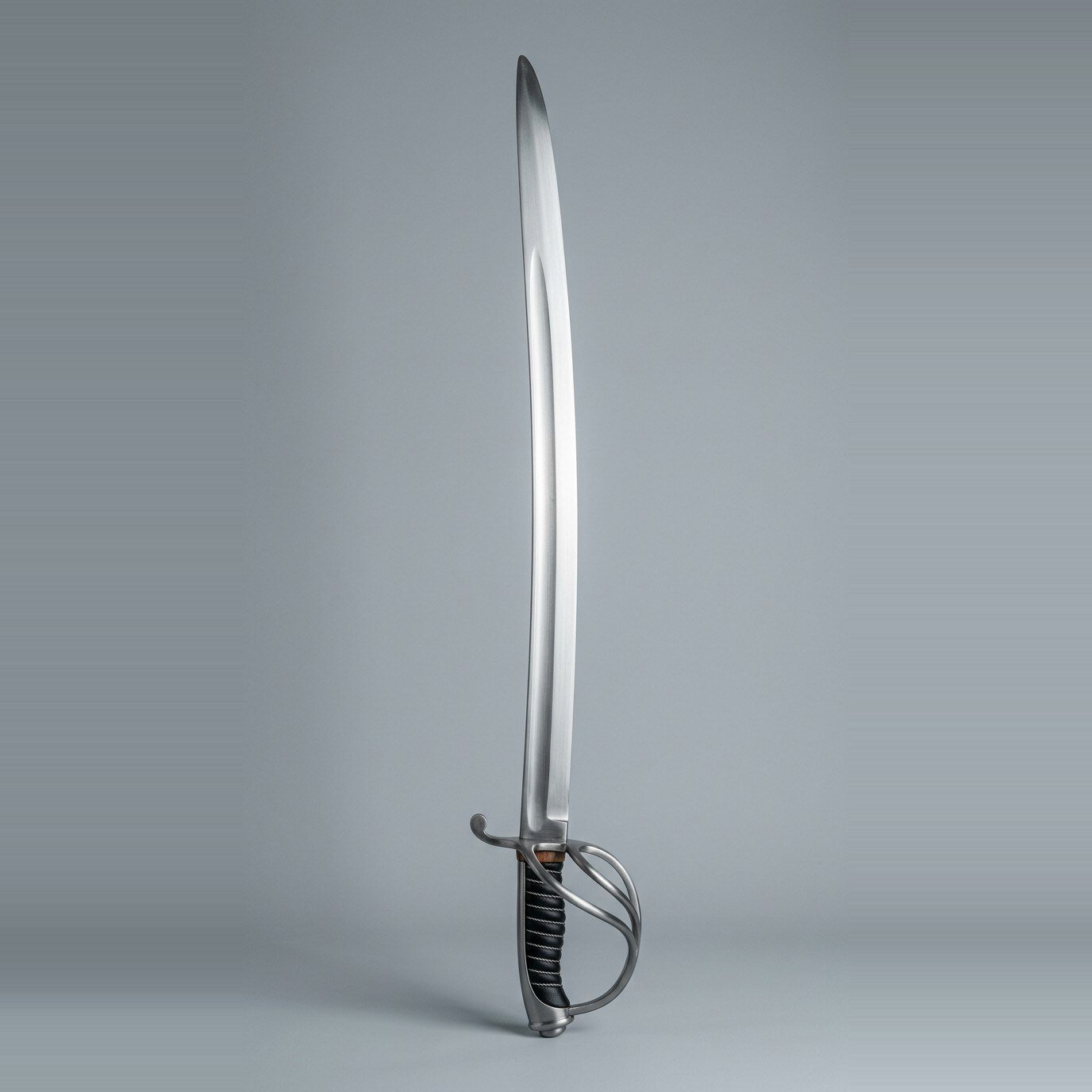 Three bar hilt sabre trainer Three bar hilt sabre trainer with a curved single edged blade, wire over leather grip and a backstrap cap shown against a plain studio backdrop