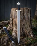Triquetra damascus sword with a pattern welded Viking blade, three lobed pommel and black leather grip standing against a weathered tree stump